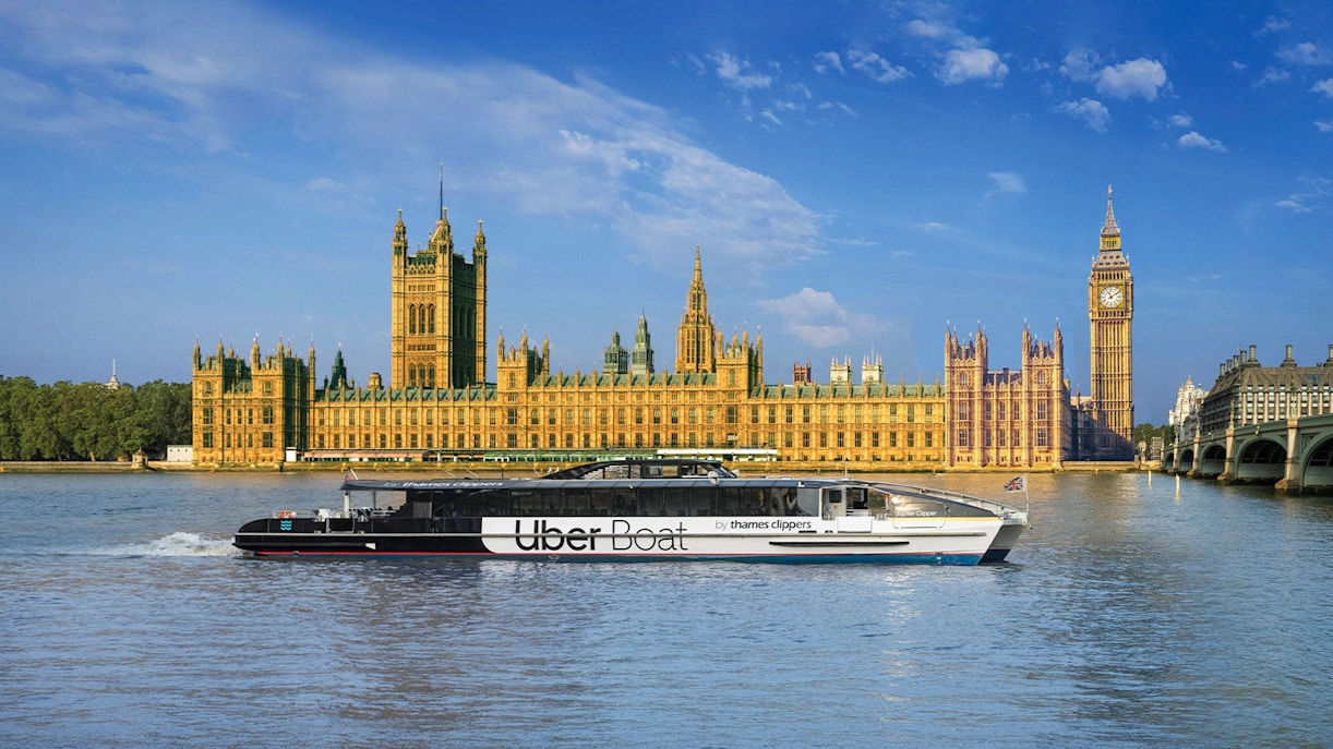 Uber Boat on Thames River passing Westminster Palace, London.
