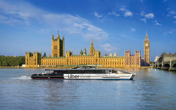 Uber Boat on Thames River passing Westminster Palace, London.