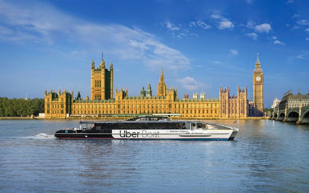 Uber Boat on Thames River passing Westminster Palace, London.