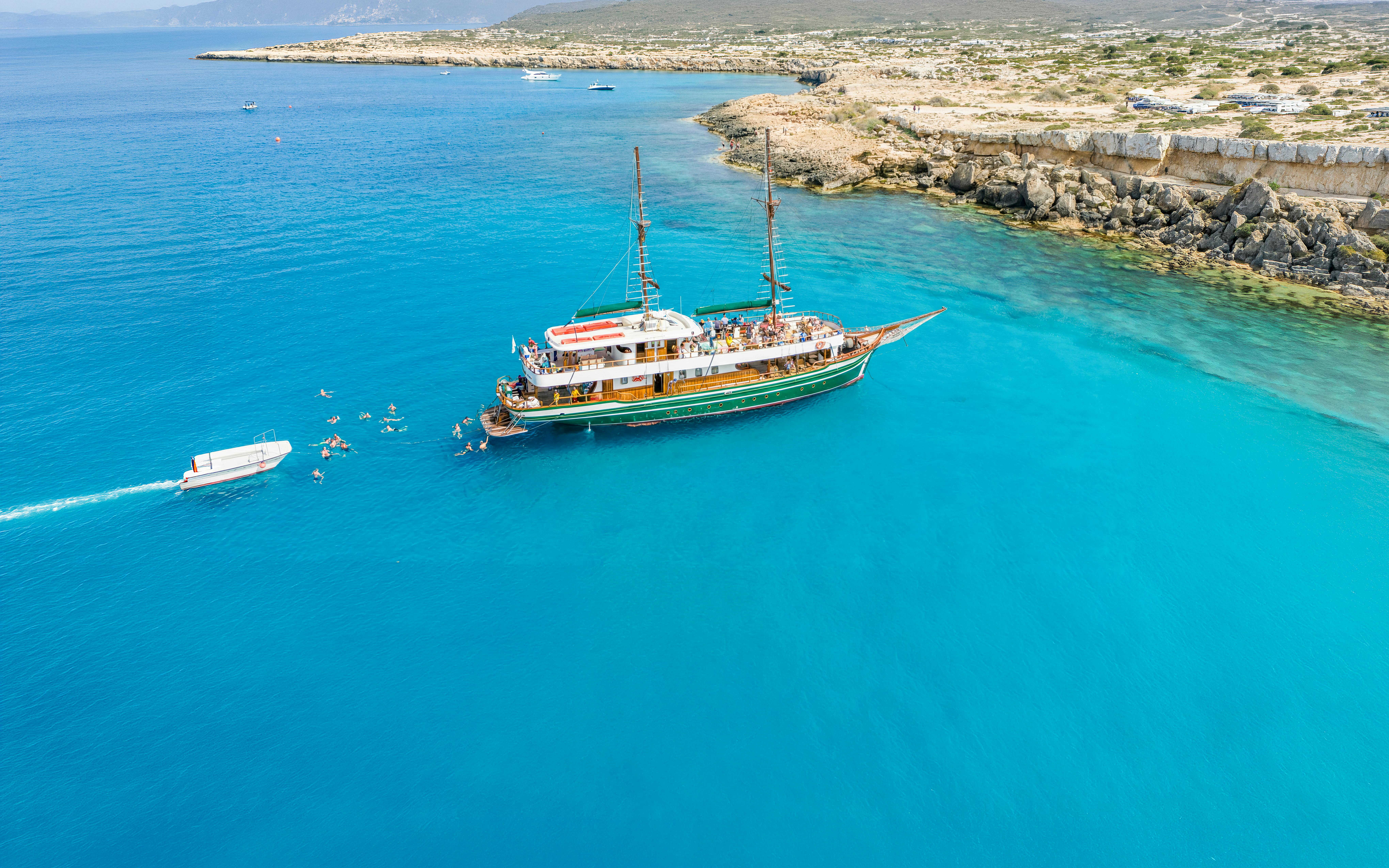 Cruise ship near Ayia Napa coast with swimmers in Blue Lagoon waters.