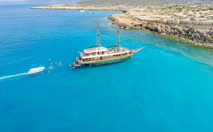 Cruise ship near Ayia Napa coast with swimmers in Blue Lagoon waters.