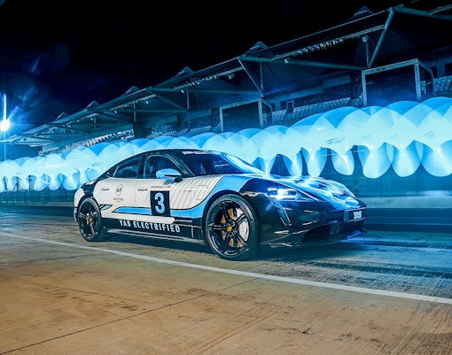 Porsche Taycan Turbo on Yas Marina Circuit at night with blue lights.