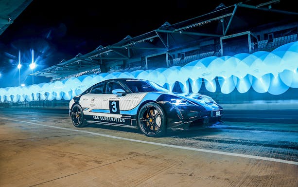 Porsche Taycan Turbo on Yas Marina Circuit at night with blue lights.