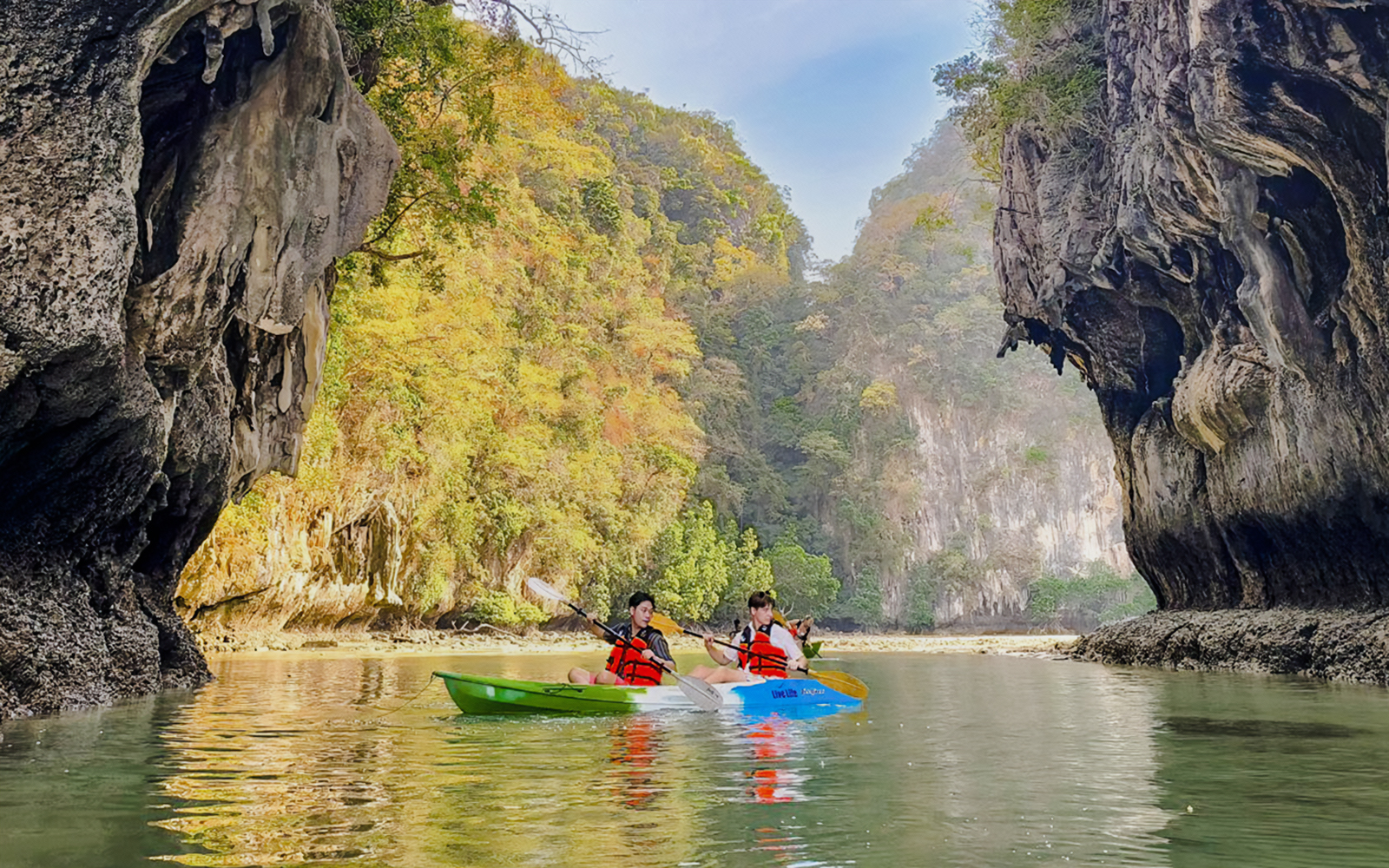 Kayakers paddling in Krabi with limestone cliffs in the background.