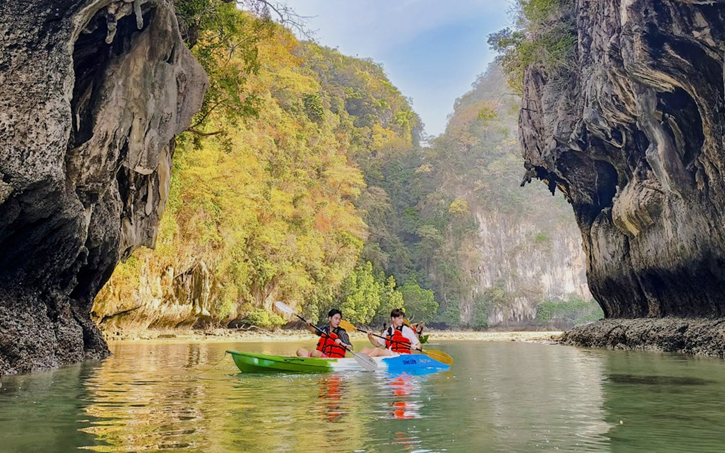 Kayakers paddling in Krabi with limestone cliffs in the background.