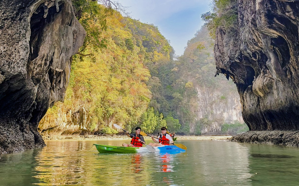 Kayakers paddling in Krabi with limestone cliffs in the background.