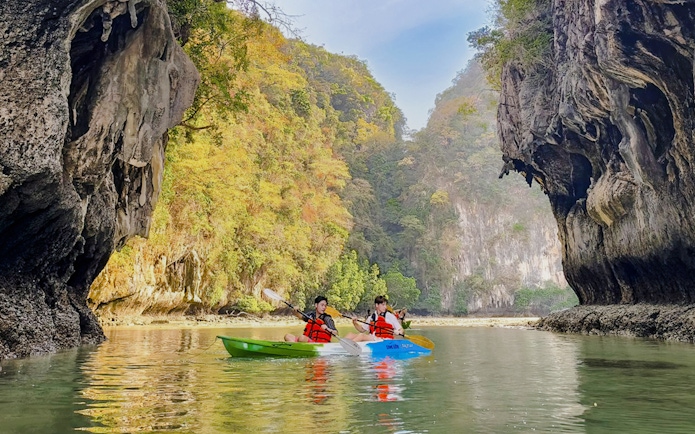 Kayakers paddling in Krabi with limestone cliffs in the background.