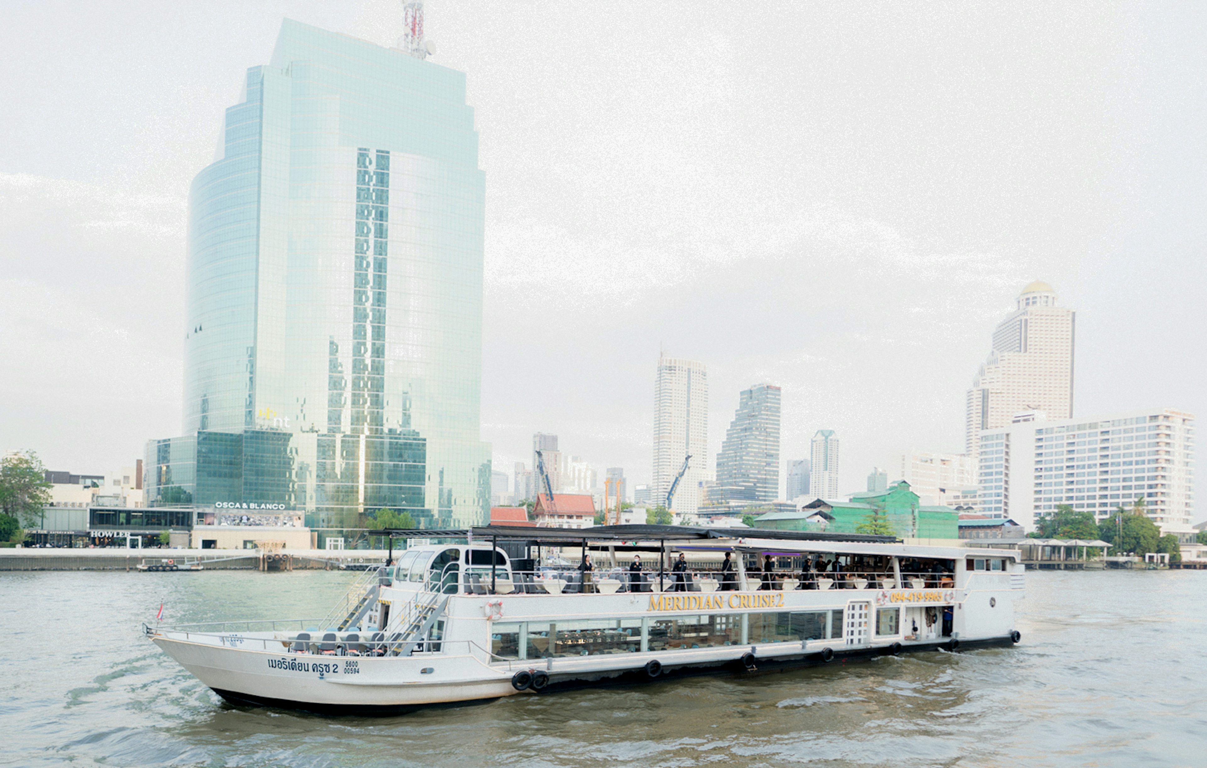 Meridian Dinner Cruise boat on a river with city skyline in the background.
