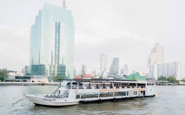 Meridian Dinner Cruise boat on a river with city skyline in the background.