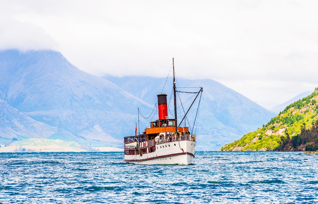 TSS Earnslaw steamship moored at Lake Wakatipu quayside with distant hills and mountains.