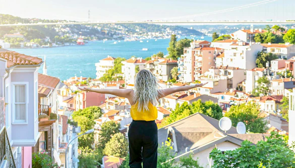 Person overlooking Istanbul rooftops with Bosphorus Bridge in the background.