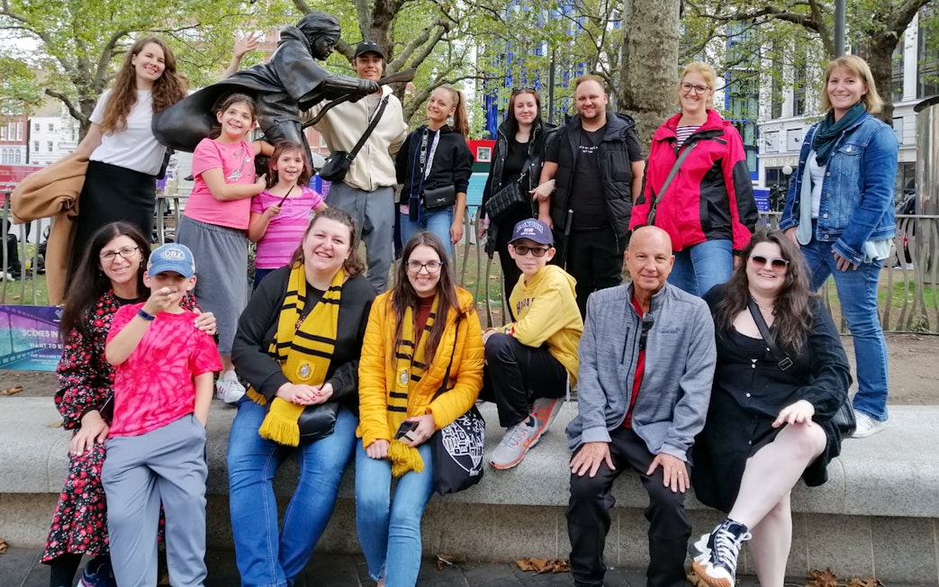 Group of tourists at Harry Potter film location in London with a broomstick statue.