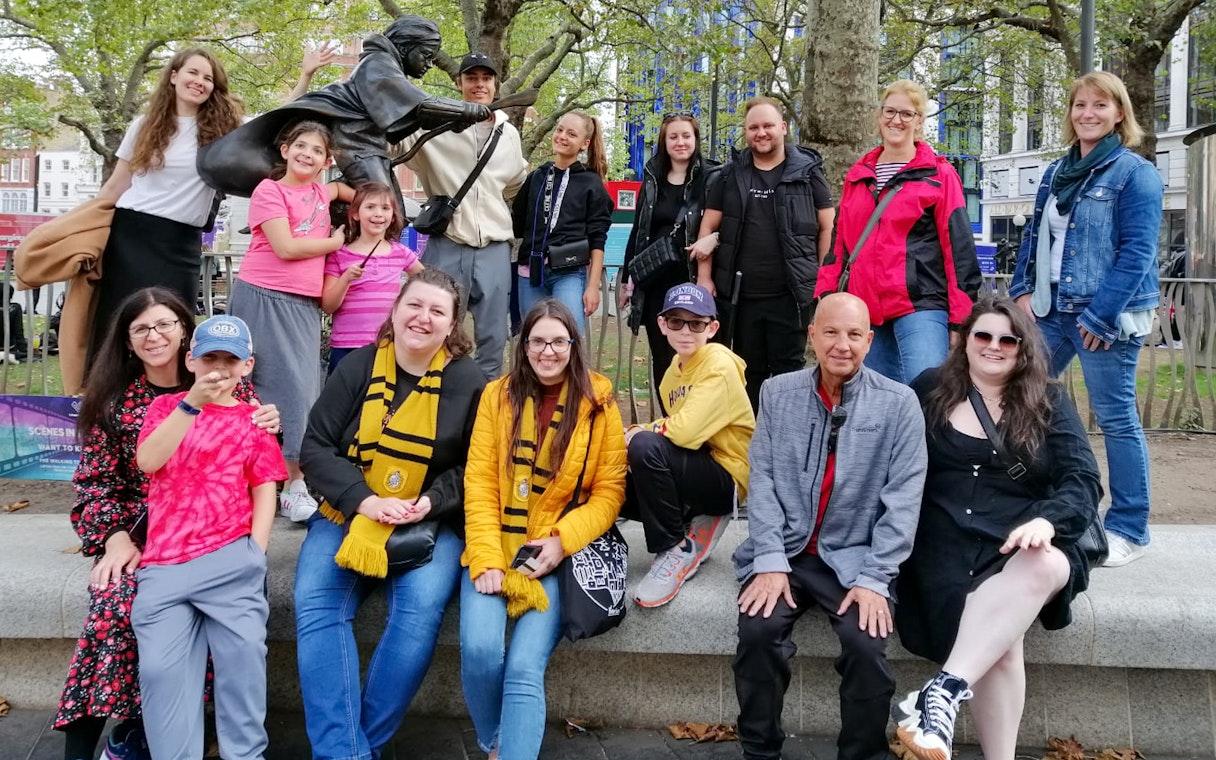 Group of tourists at Harry Potter film location in London with a broomstick statue.