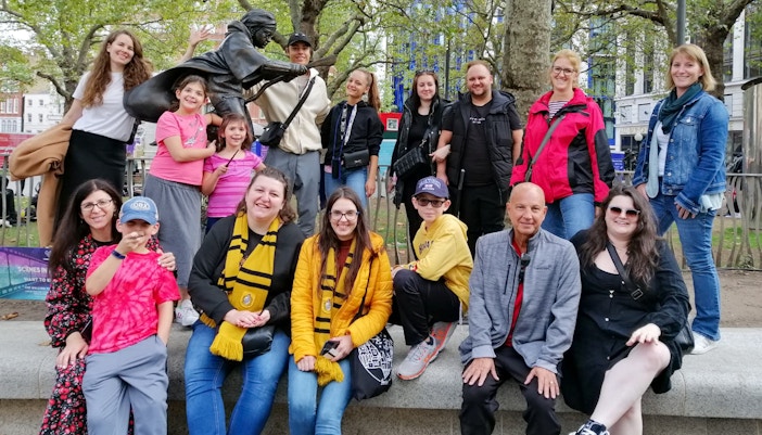 Group of tourists at Harry Potter film location in London with a broomstick statue.