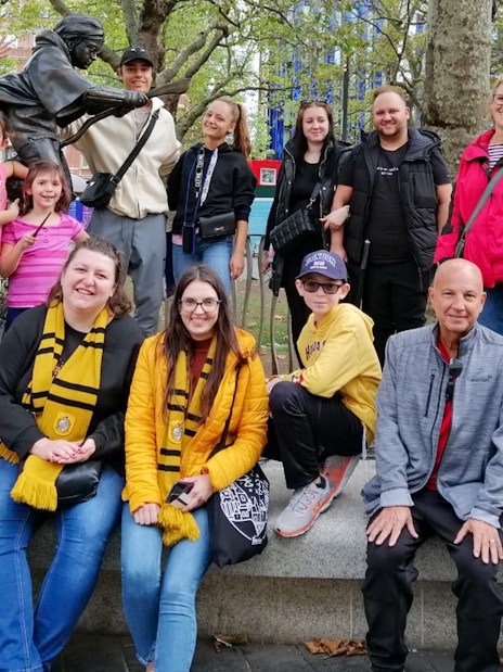 Group of tourists at Harry Potter film location in London with a broomstick statue.