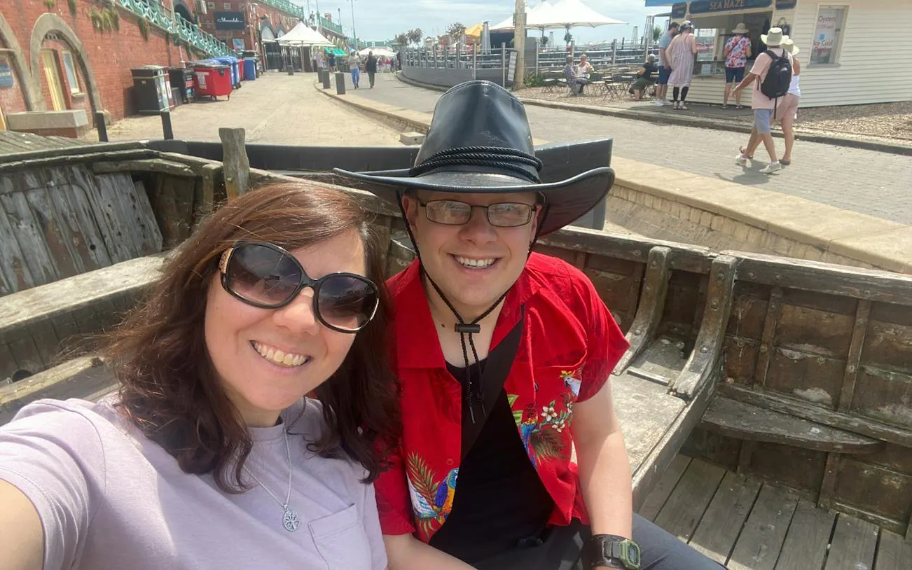 Selfie of two people sitting in a wooden boat on Brighton seafront, part of a city exploration game.