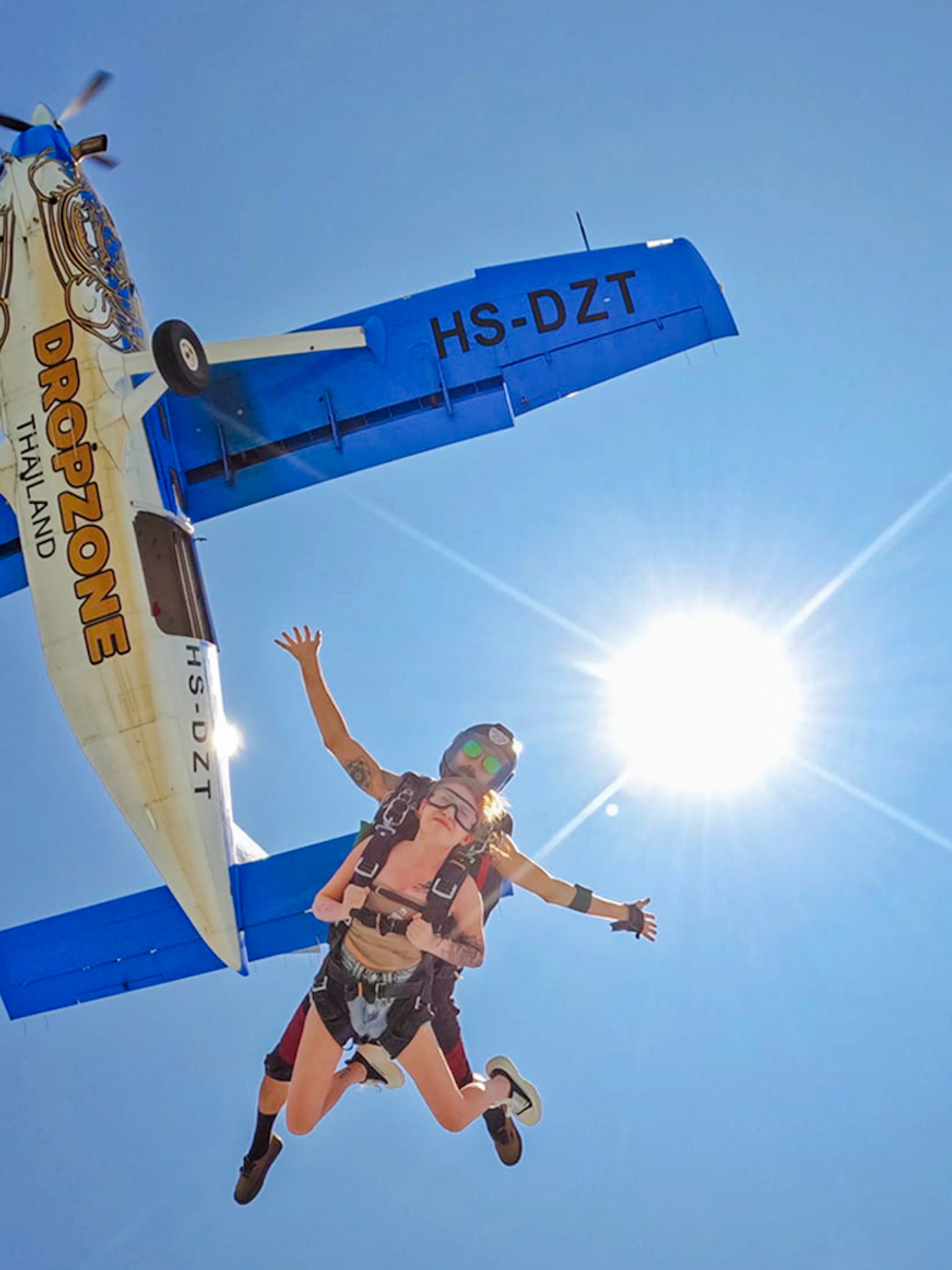 Tandem skydive over Pattaya from 13,000 ft with clear ocean view and airplane above.