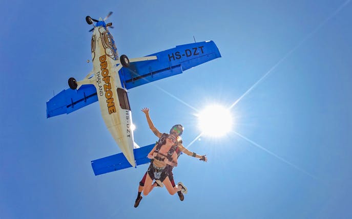 Tandem skydive over Pattaya from 13,000 ft with clear ocean view and airplane above.