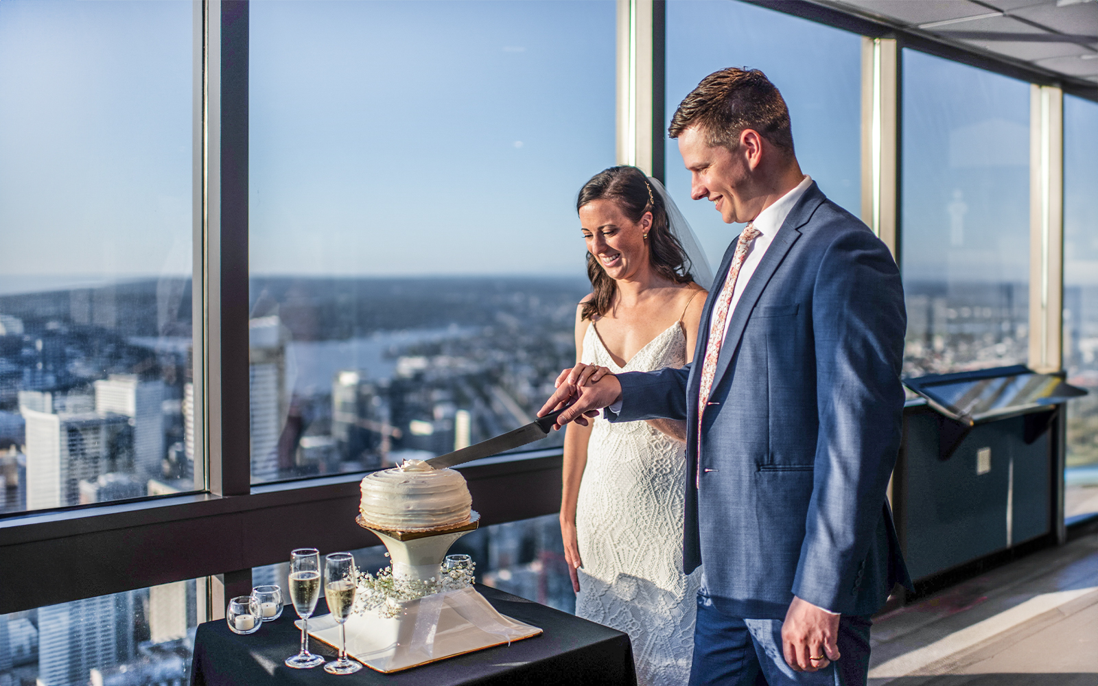 Couple cutting cake at Sky View Observatory with cityscape view.