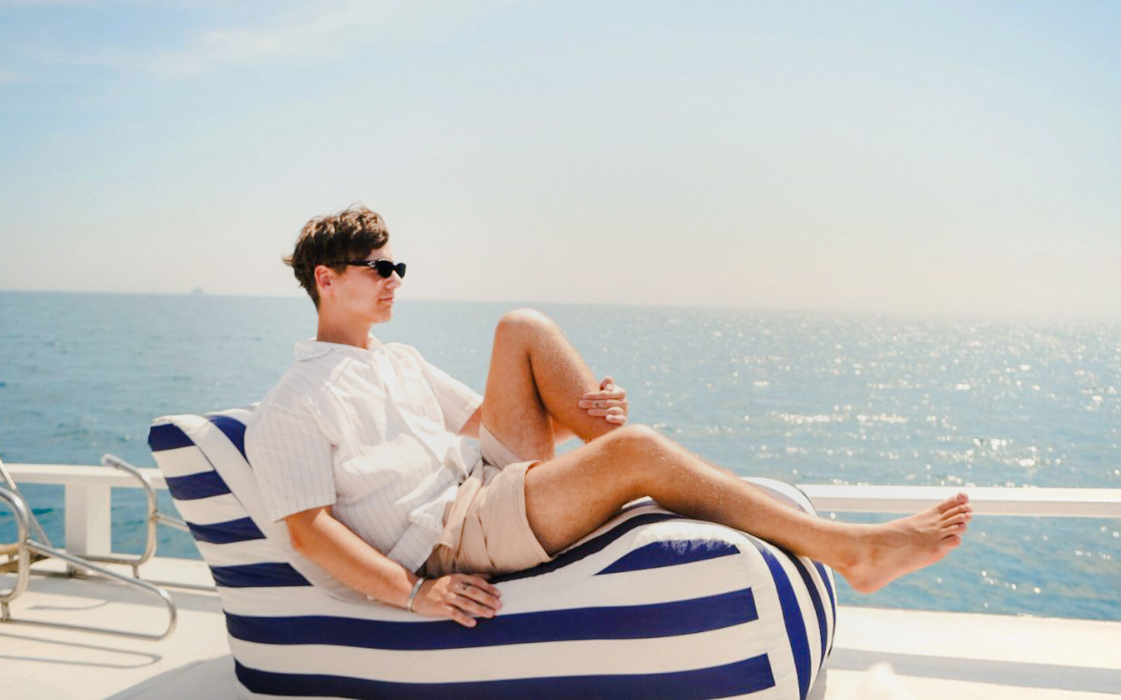 Tourist relaxing on a longtail boat deck with ocean view.