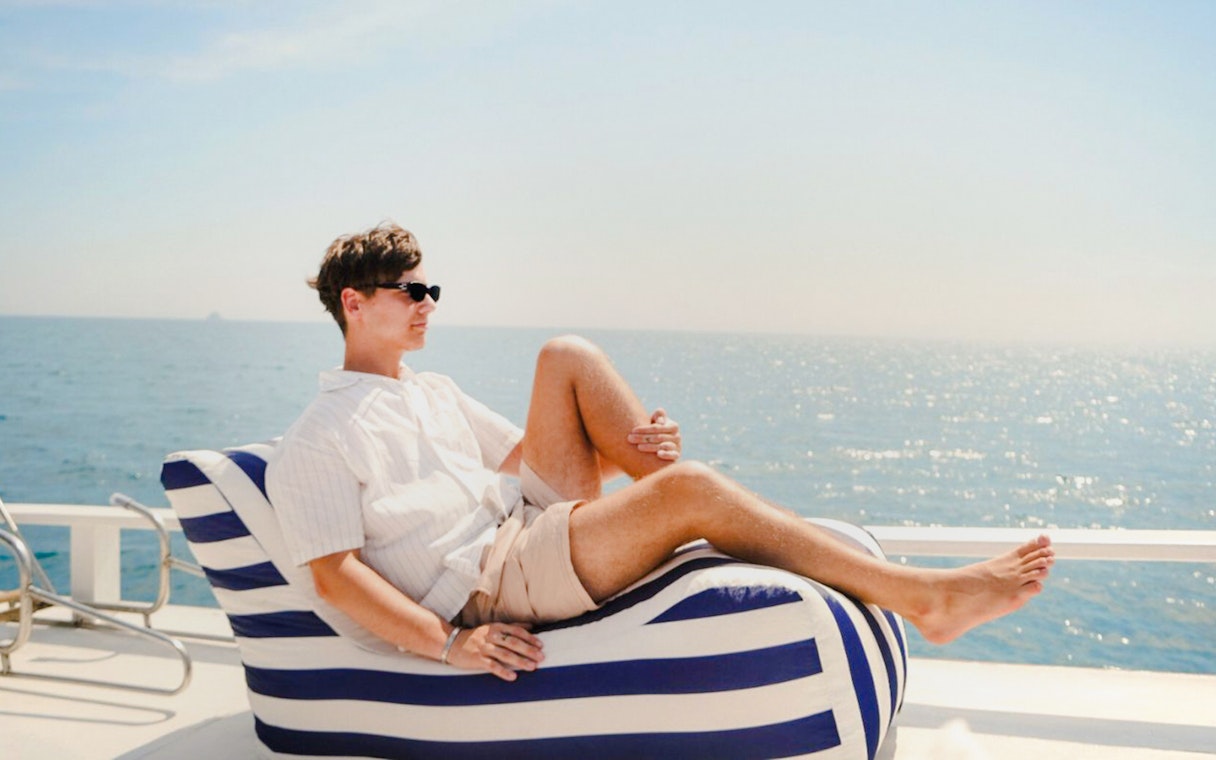Tourist relaxing on a longtail boat deck with ocean view.
