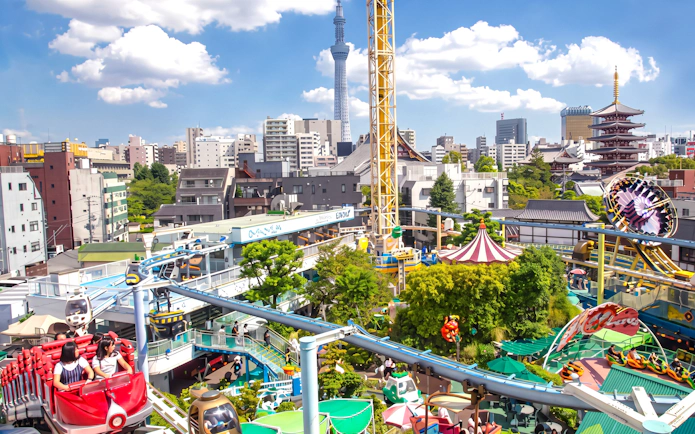 Asakusa Hanayashiki amusement park with rides, roller coasters, and cityscape in Tokyo.