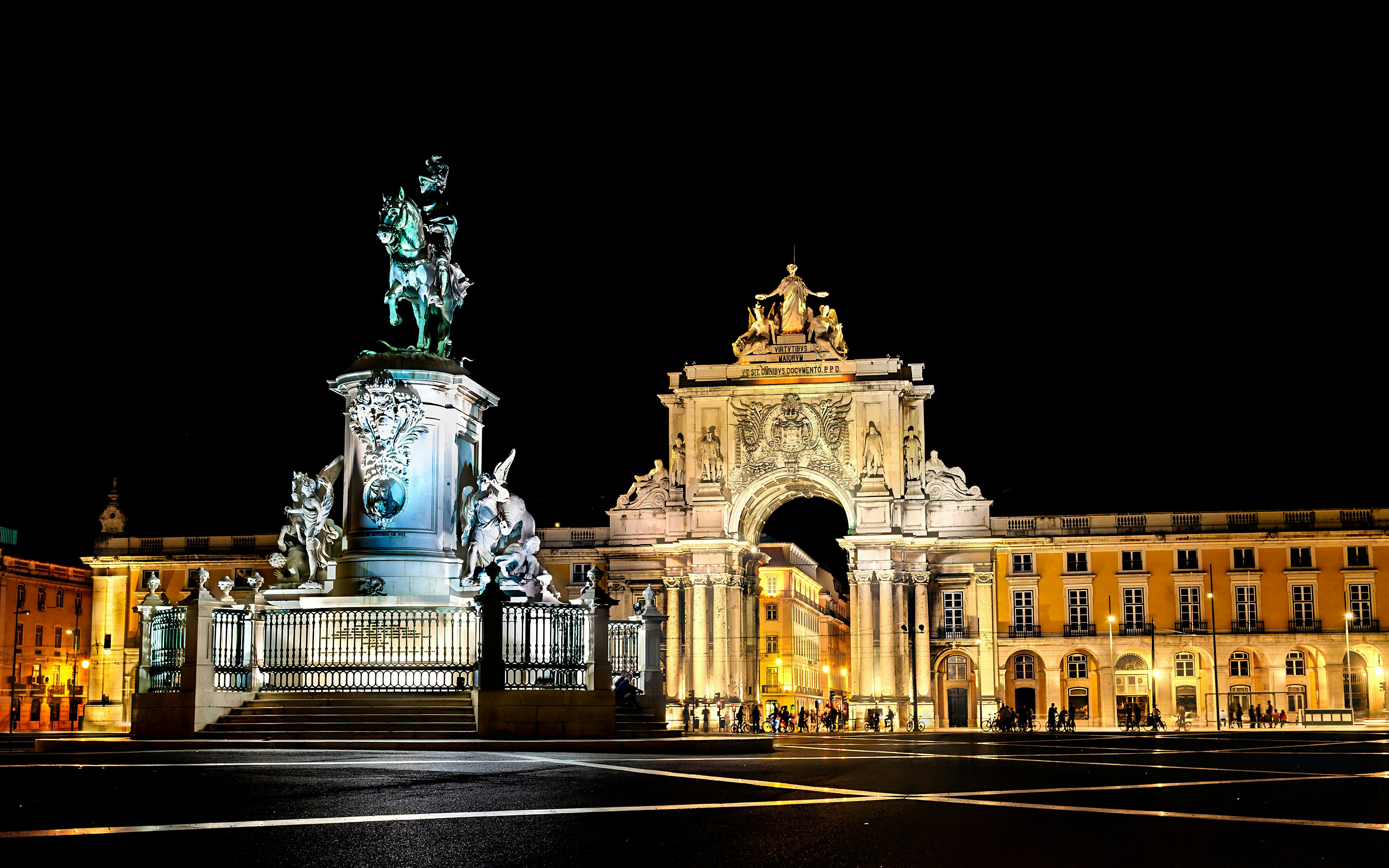 Commerce Square in Lisbon, Portugal illuminated at night with equestrian statue and arch.