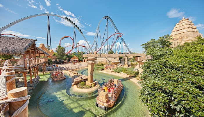 Visitors enjoying rides at PortAventura Park, Spain, with roller coasters and vibrant attractions in the background.