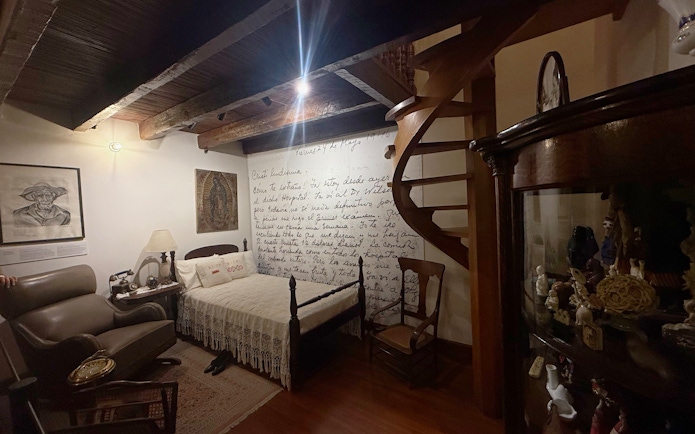 Frida Kahlo Museum room with bed, spiral staircase, and wall art at La Casa Roja.