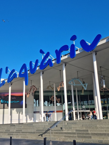Entrance of L'Aquàrium de Barcelona with blue signage and modern architecture.