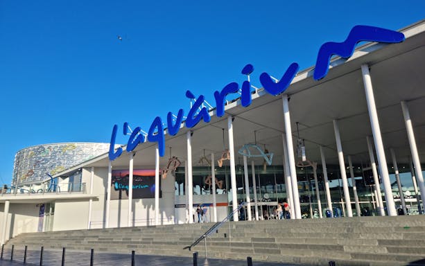 Entrance of L'Aquàrium de Barcelona with blue signage and modern architecture.