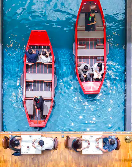Gondola rides inside Marina Bay Sands, Singapore, with diners seated nearby.