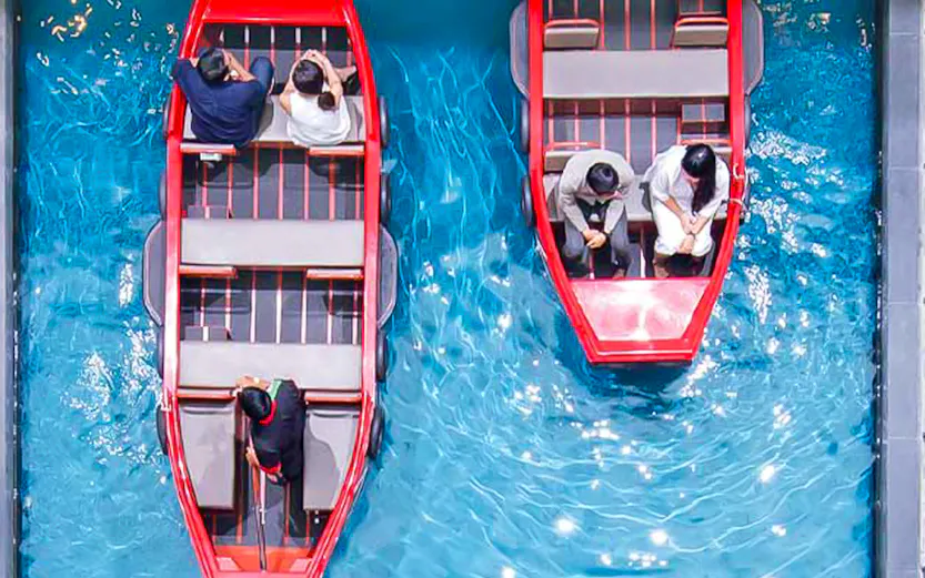 Gondola rides inside Marina Bay Sands, Singapore, with diners seated nearby.