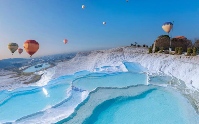 Hot air balloons floating above Pamukkale's travertine terraces, Turkey.