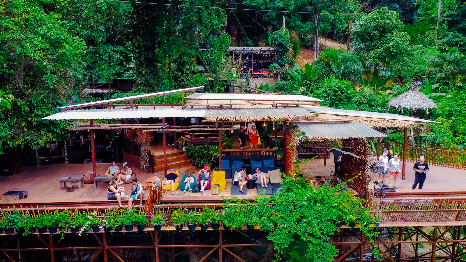 Visitors relaxing at a treetop cafe with lush greenery, part of the Tree Bridge Zipline tour in Koh Samui.