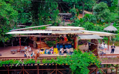 Visitors relaxing at a treetop cafe with lush greenery, part of the Tree Bridge Zipline tour in Koh Samui.