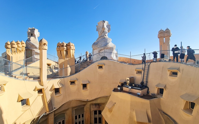 La Pedrera Casa Mila rooftop with unique chimneys and visitors in Barcelona.