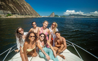 Tourists enjoying a boat ride in Guanabara Bay, Rio de Janeiro with Sugarloaf Mountain in the background.