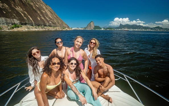 Tourists enjoying a boat ride in Guanabara Bay, Rio de Janeiro with Sugarloaf Mountain in the background.
