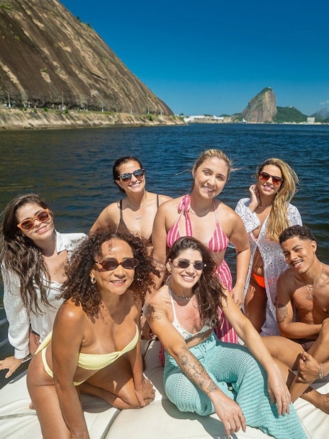 Tourists enjoying a boat ride in Guanabara Bay, Rio de Janeiro with Sugarloaf Mountain in the background.