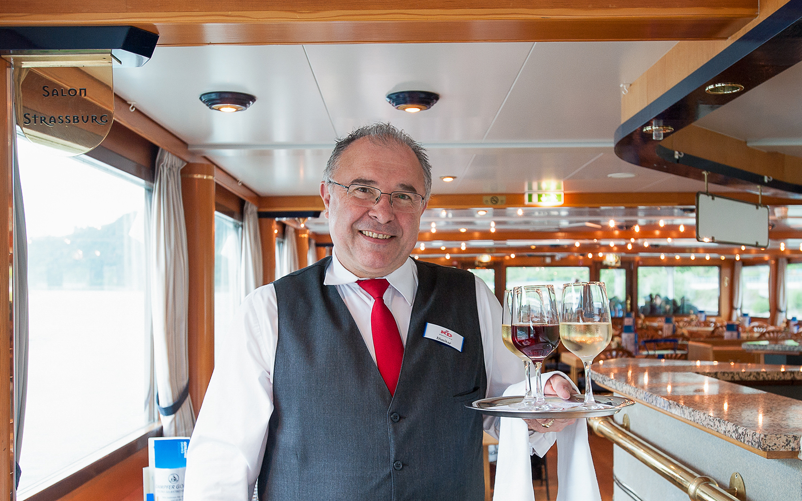 Server on paddle steamer Goethe offering wine during nostalgia cruise.
