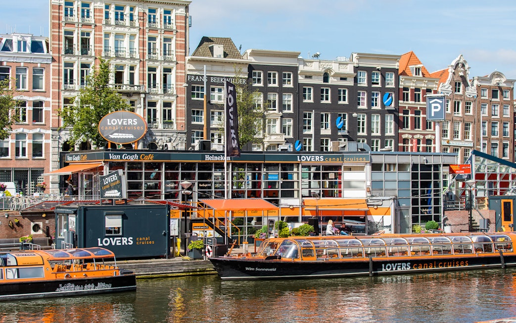 Amsterdam canal cruise boat docked near historic buildings.