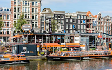 Amsterdam canal cruise boat docked near historic buildings.