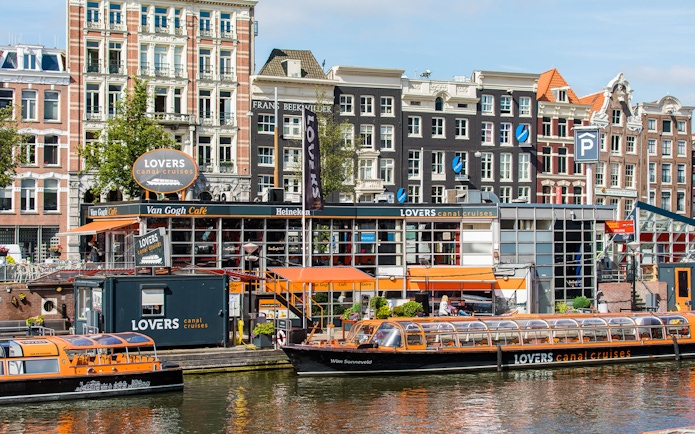 Amsterdam canal cruise boat docked near historic buildings.