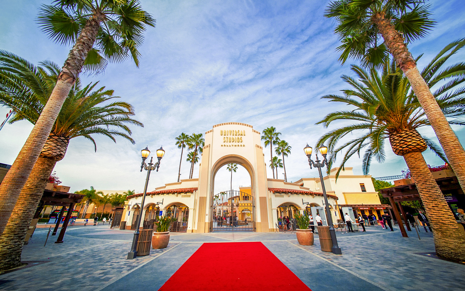 Entrance archway of Universal Studios Hollywood with palm trees and red carpet.