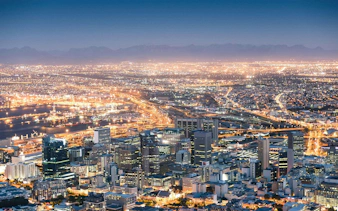 Cape Town cityscape at night with illuminated buildings and harbor.