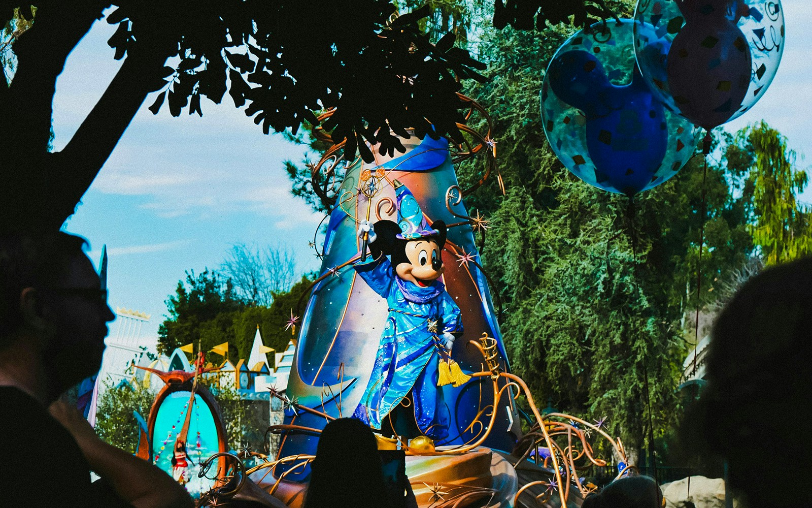 Mickey Mouse in wizard costume on parade float at theme park.
