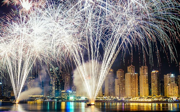 Dubai New Year 2024 fireworks over city skyline at night.