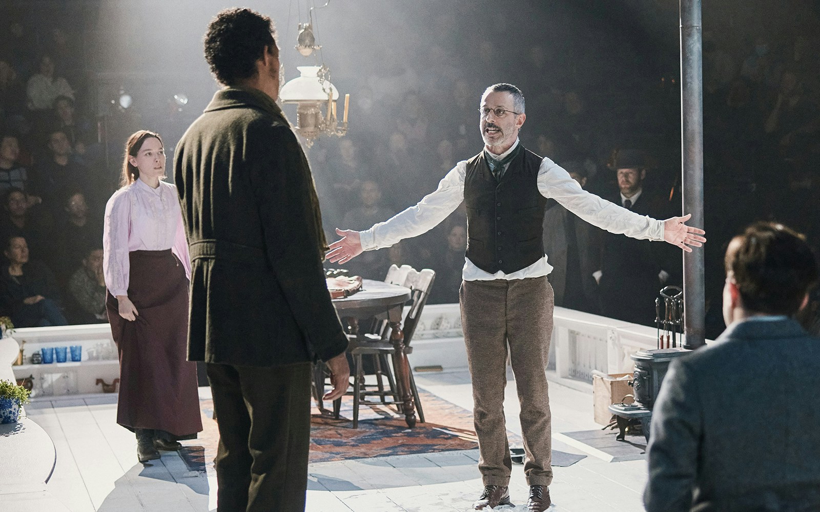 Theater performance of "An Enemy of the People" with actors in period costumes on stage.