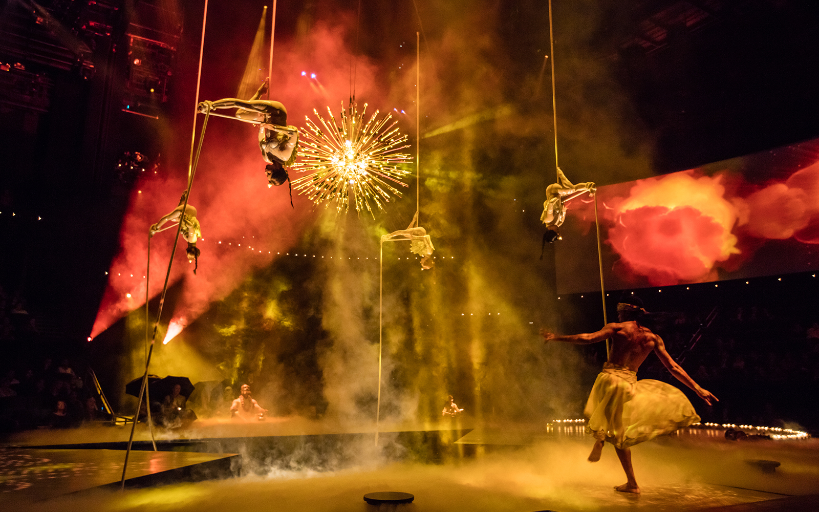 Aerial performers in The Beatles LOVE show with vibrant lighting and stage effects.